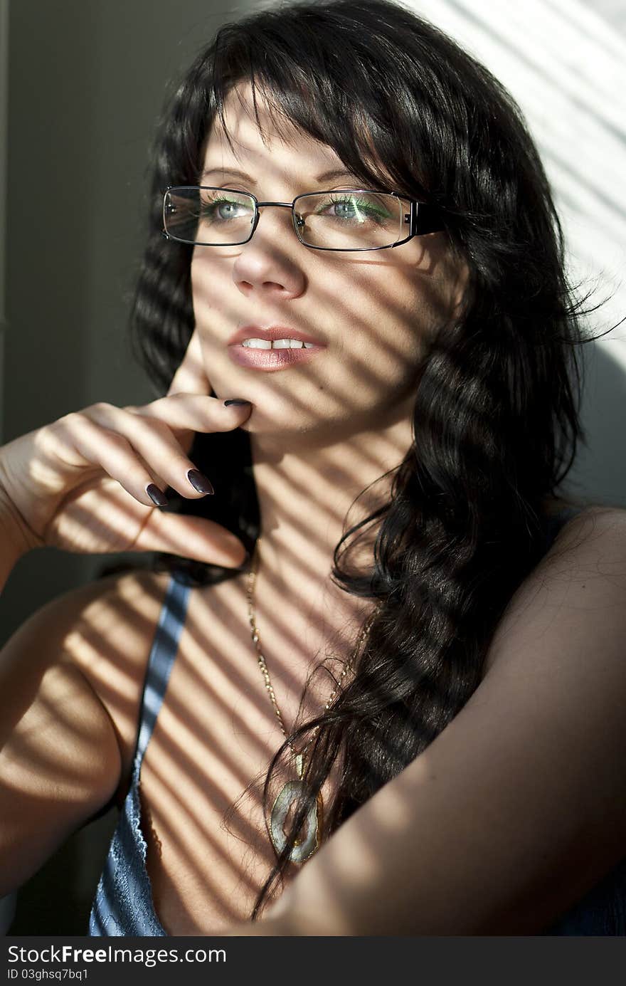 Girl with glasses sitting at the window with shutters. Girl with glasses sitting at the window with shutters