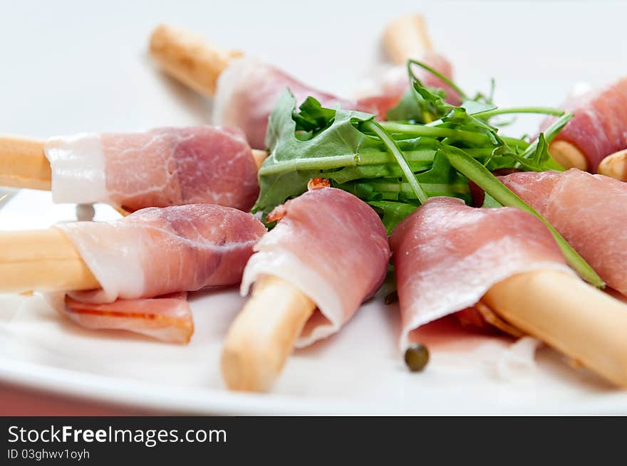 Wrap slices of ham  on a white plate. Wrap slices of ham  on a white plate.