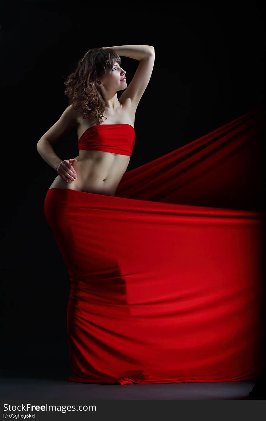 The girl in a red dress against a dark background