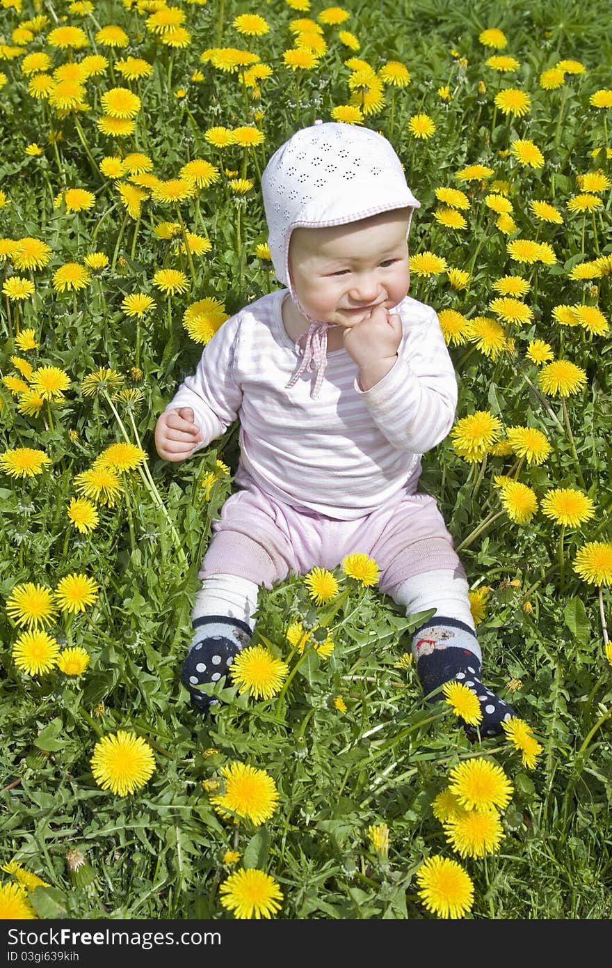 Baby sitting in meadow with dandelions