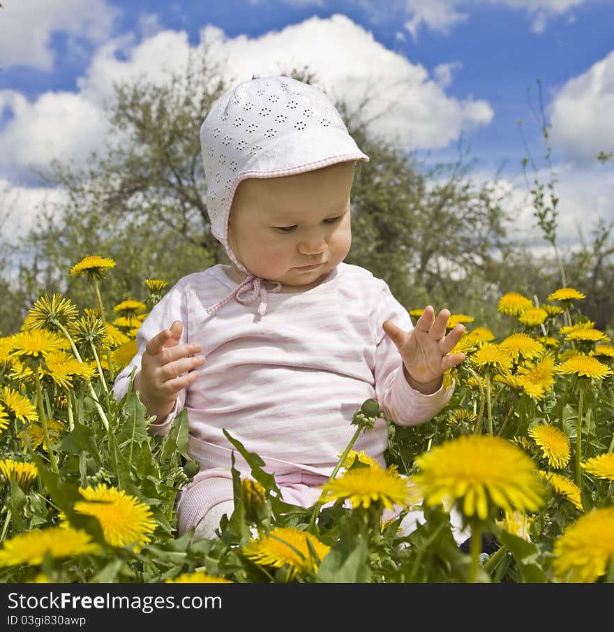 10 months old baby sitting in meadow with dandelions