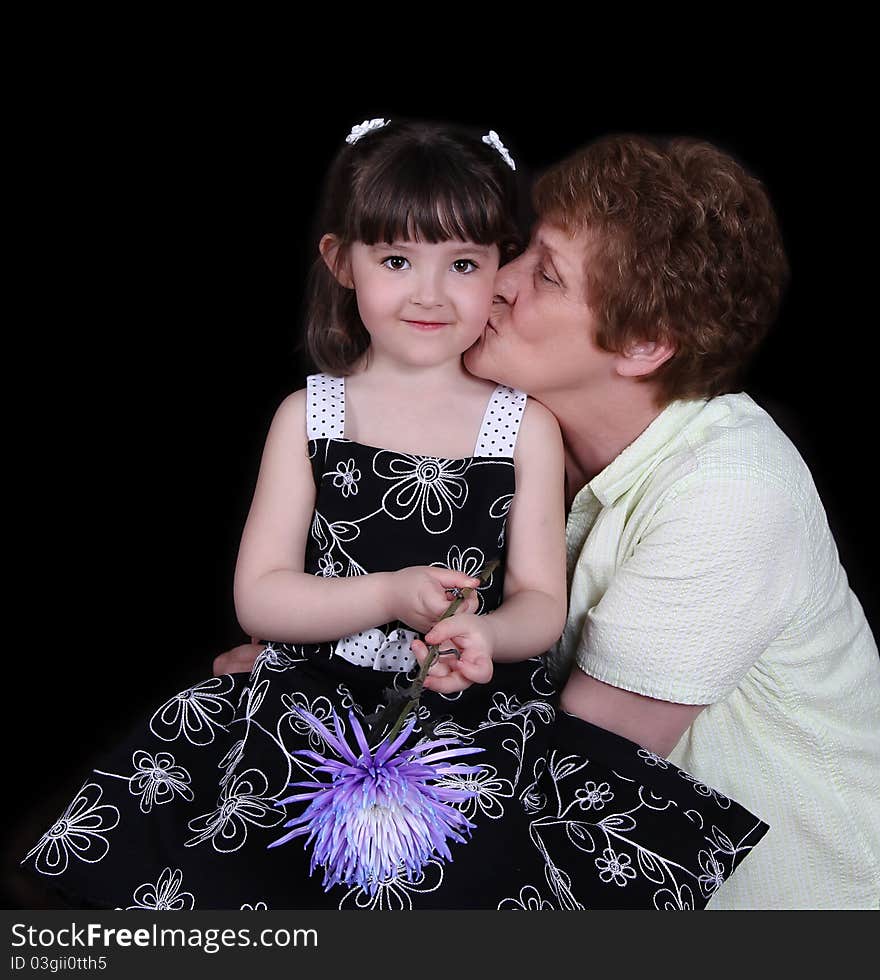 Proud grand-mother kissing smiling grand-daughter on cheek. isolated on black. Proud grand-mother kissing smiling grand-daughter on cheek. isolated on black