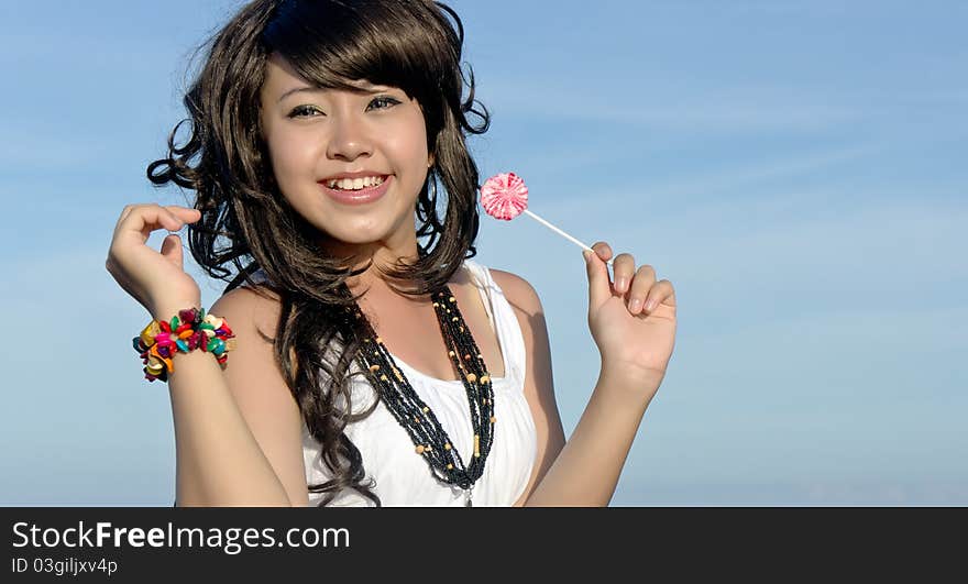 Young pretty asian girl enjoys eating sweets candy during holiday on tropical island. Young pretty asian girl enjoys eating sweets candy during holiday on tropical island