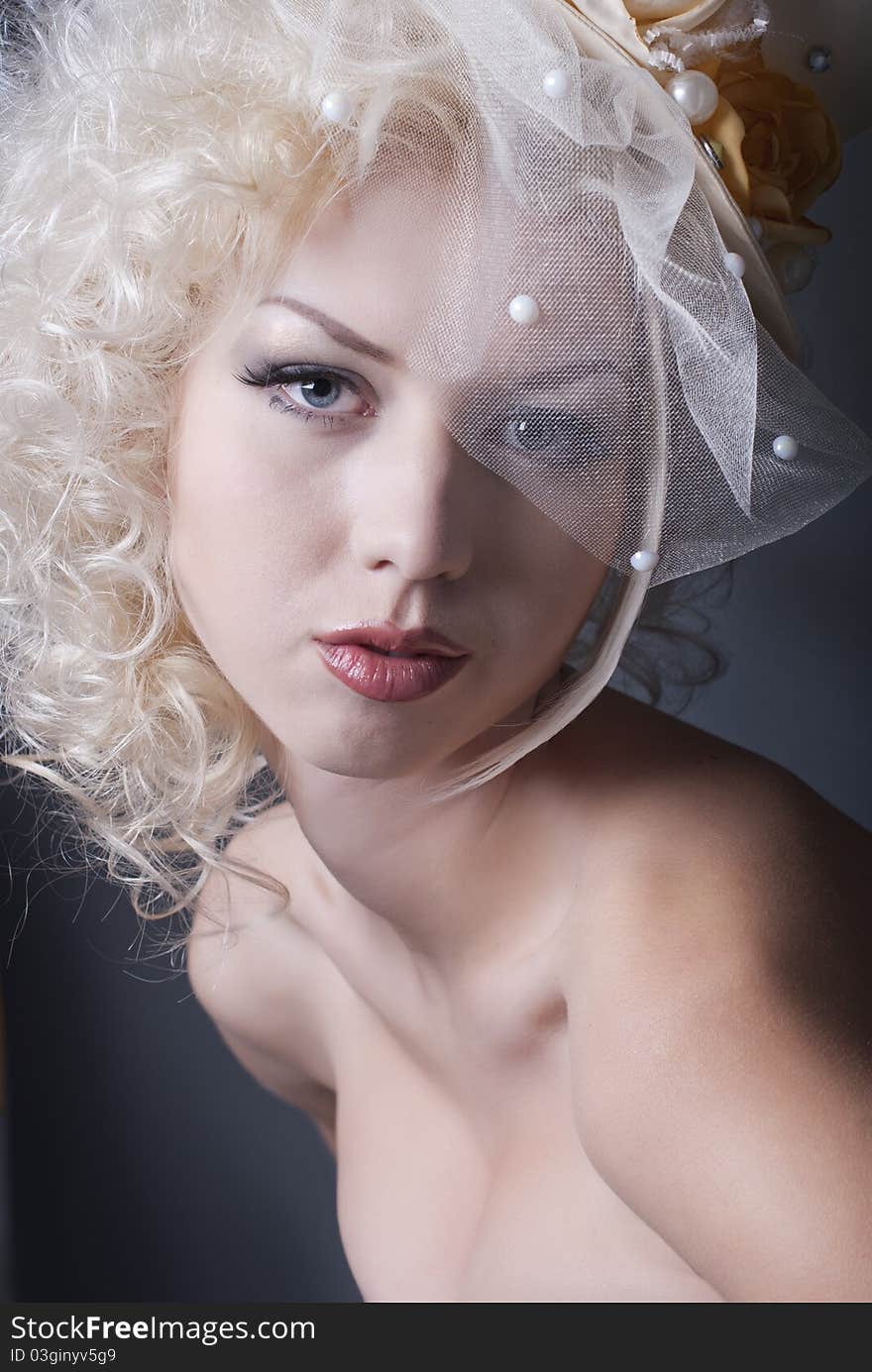 Dark portrait of blonde girl in evening dress and a bowler hat with a veil. Dark portrait of blonde girl in evening dress and a bowler hat with a veil