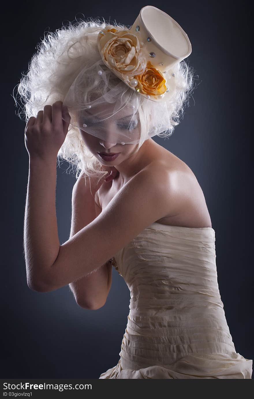 Dark portrait of blonde girl in evening dress and a bowler hat with a veil. Dark portrait of blonde girl in evening dress and a bowler hat with a veil