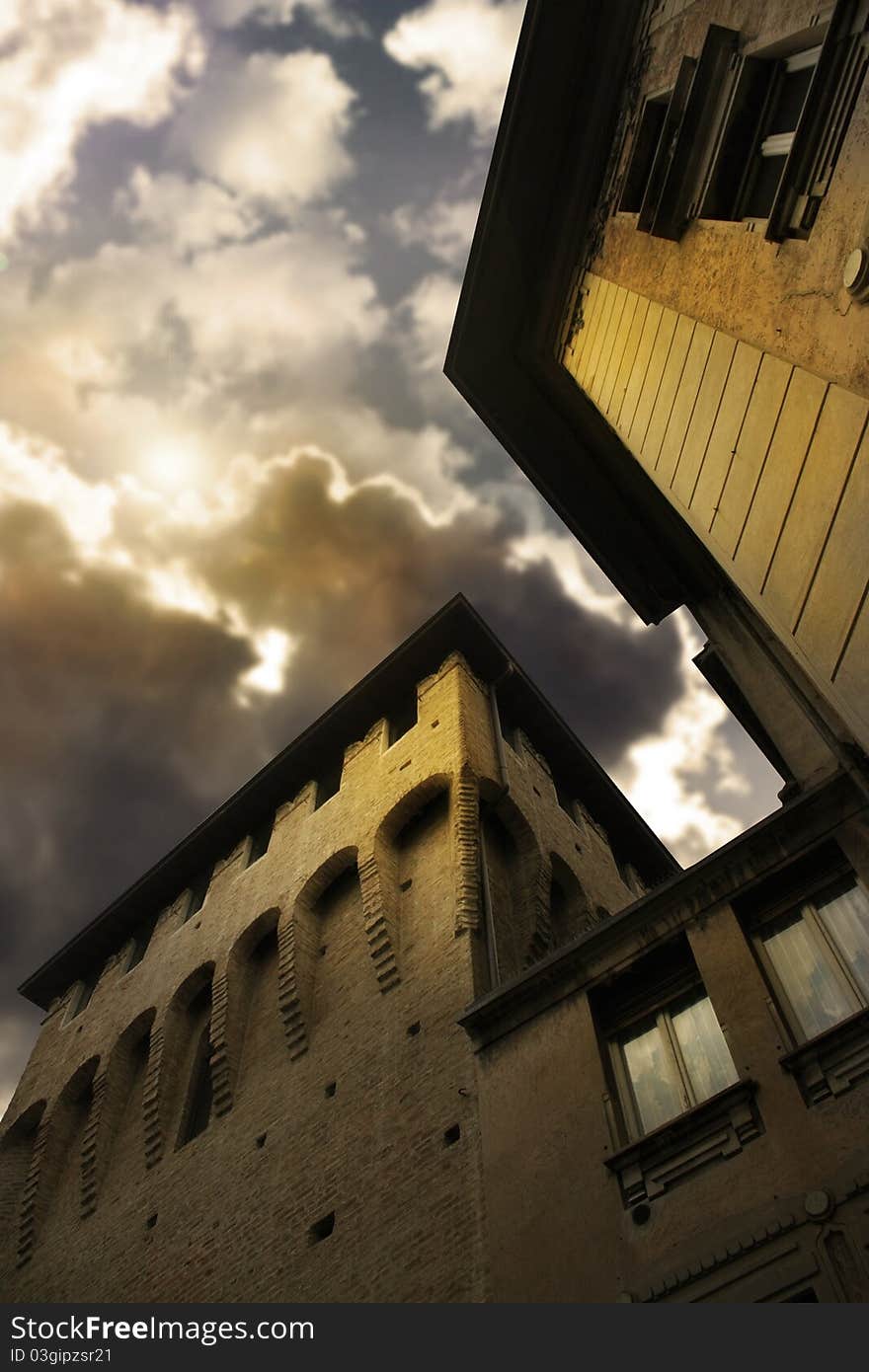 Exterior of an anicent building in Parma of Northern Italy with dramatic cloudscape and breaking sun behind