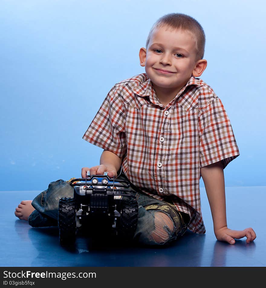 Happy boy playing with car against blue background