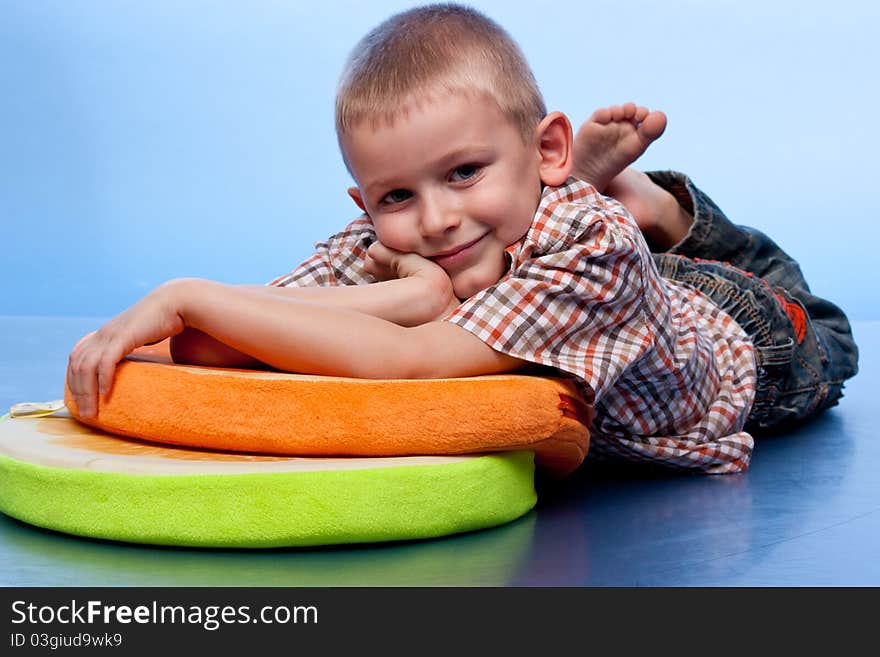 Cute boy resting on a pillow against blue background