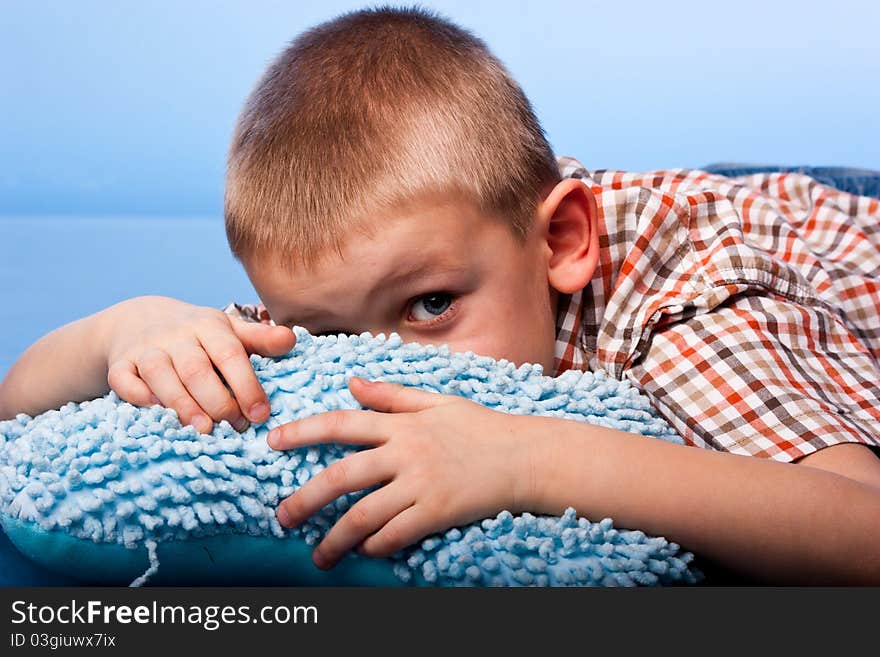 Cute boy resting on a pillow against blue background