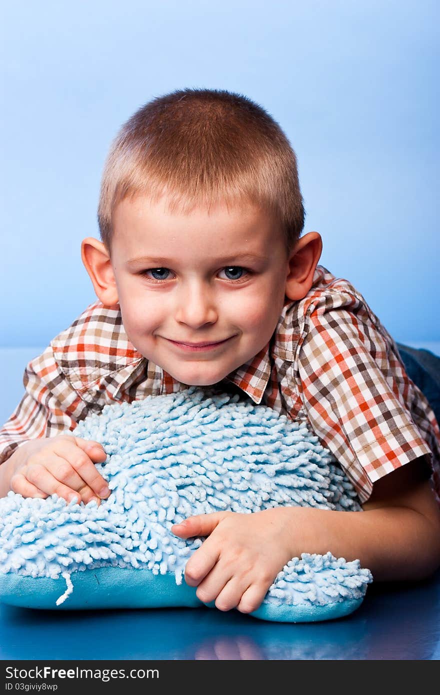 Cute boy resting on a pillow against blue background