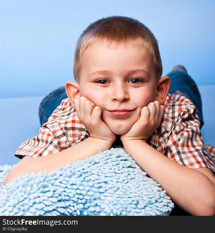 Cute boy resting on a pillow against blue background