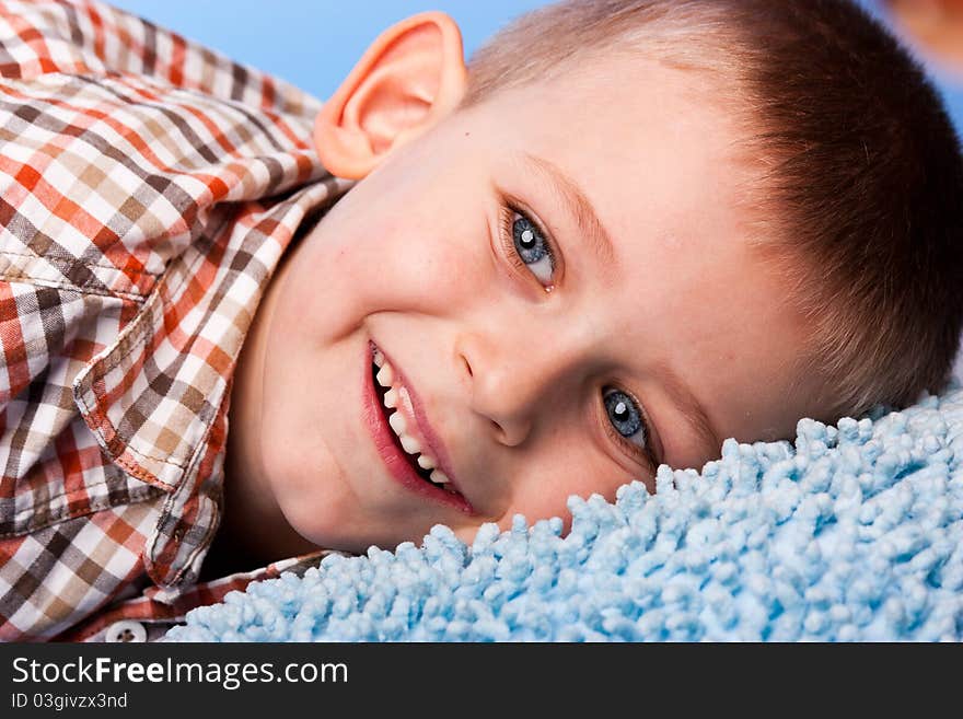 Cute boy resting on a pillow against blue background