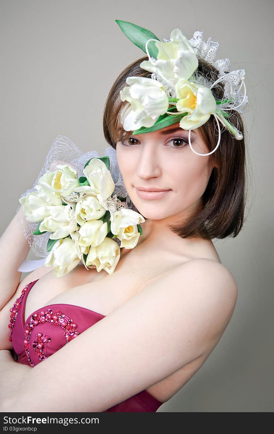 The beautiful girl holds white flowers on a gray background. The beautiful girl holds white flowers on a gray background