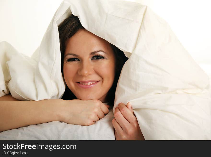 Smiling girl under white blanket