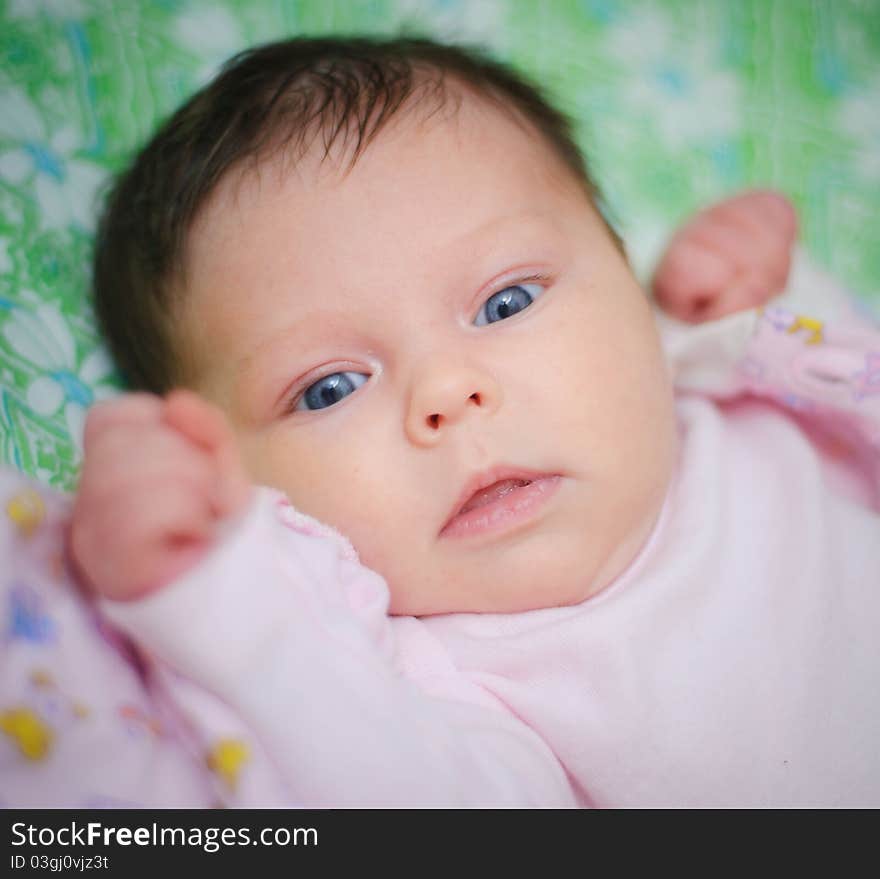 Beautiful baby girl is lying in a bed.