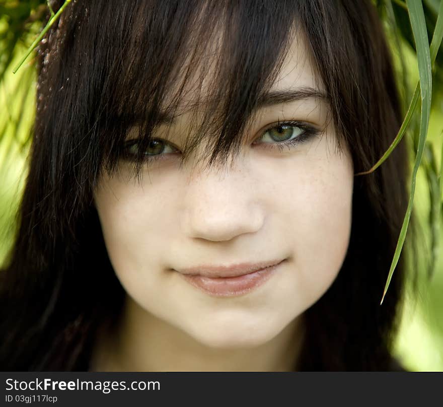 Portrait of brunette teen girl at green outdoor.