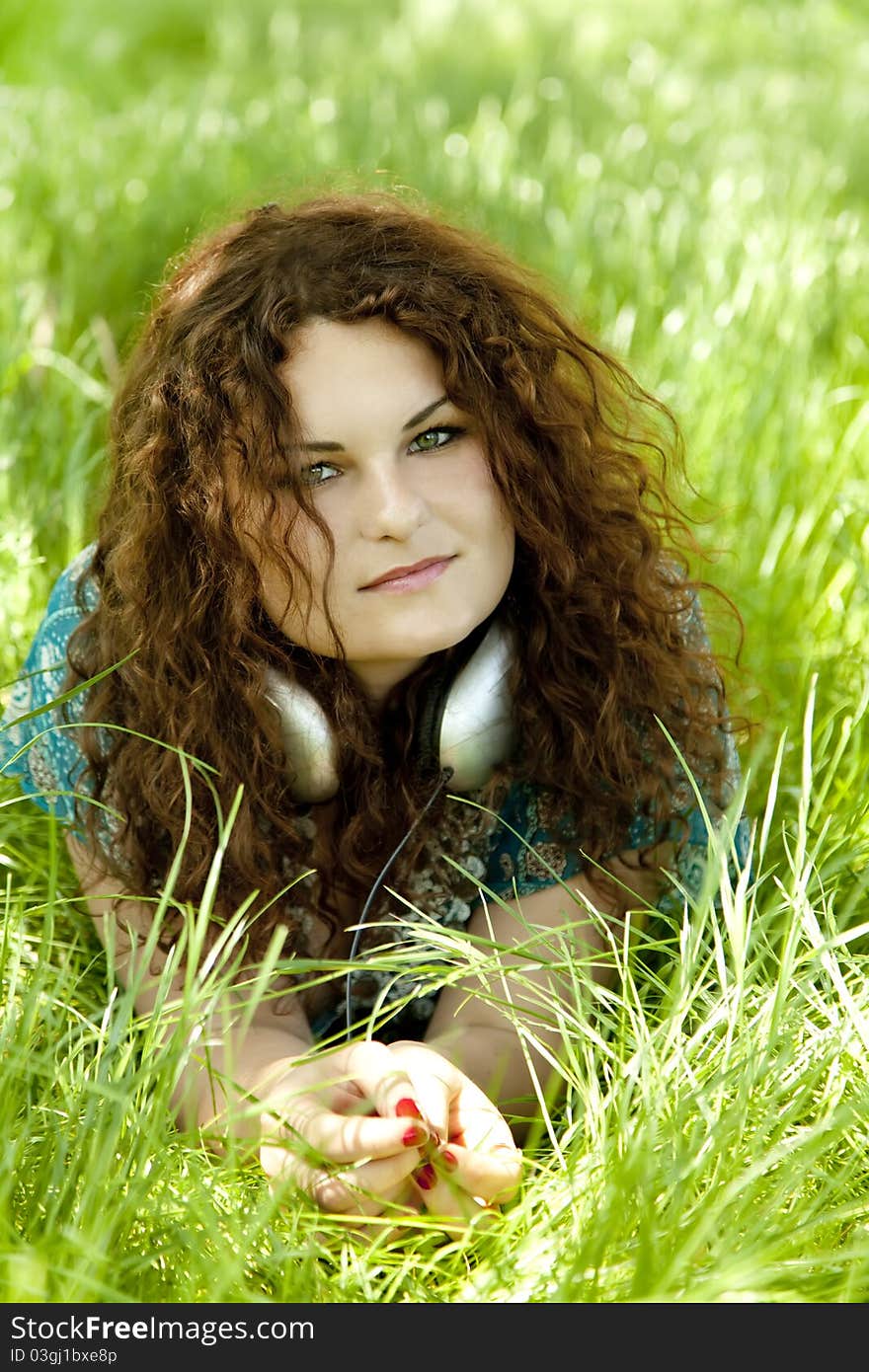 Redhead girl with headphone at green grass