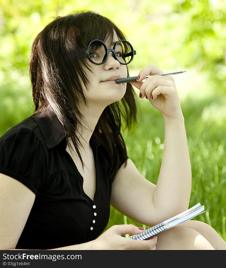 Young teen girl with notebook at green grass