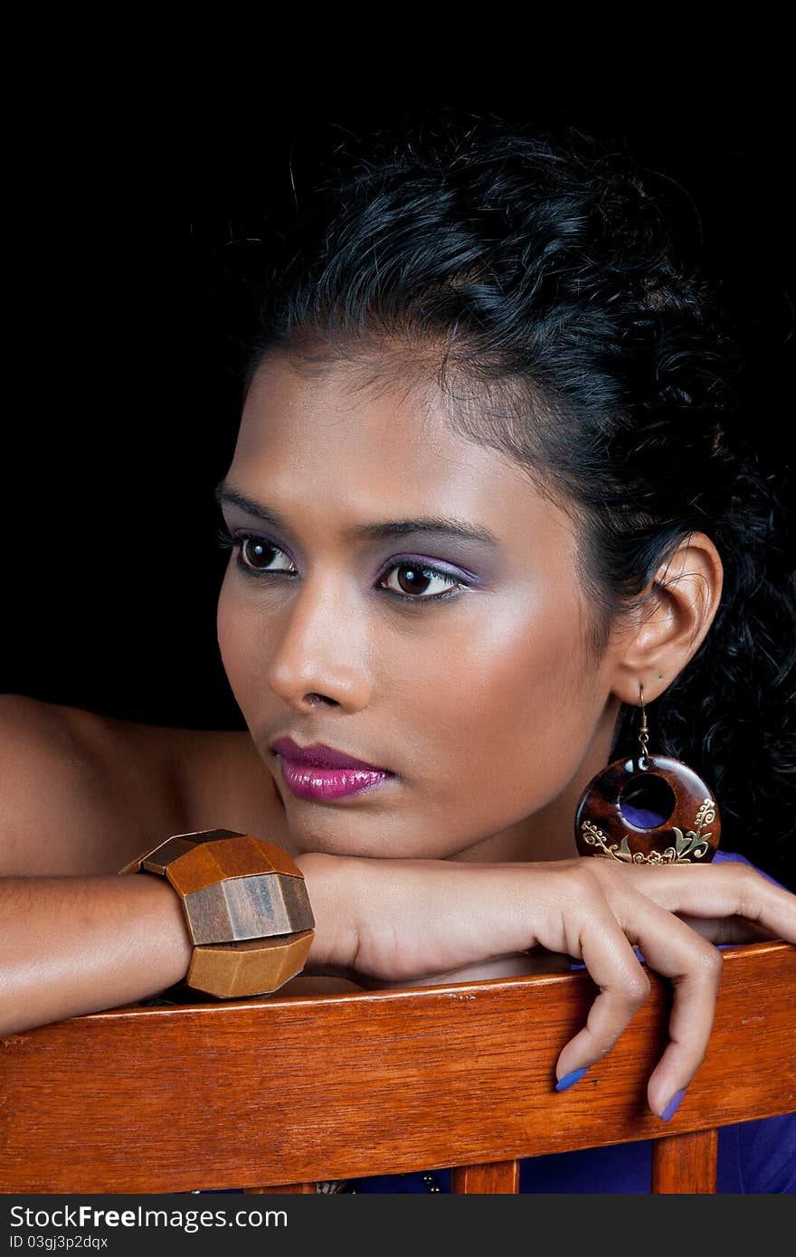 Beautiful woman of east indian ancestry sitting in chair and relaxing and isolated on a black background. Beautiful woman of east indian ancestry sitting in chair and relaxing and isolated on a black background