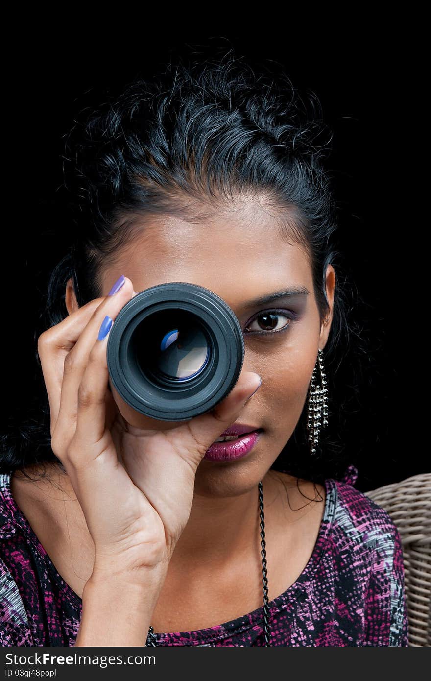 Beautiful woman of east indian ancestry wearing a wide neck top looking though the lens of a dslr camera with intent. Beautiful woman of east indian ancestry wearing a wide neck top looking though the lens of a dslr camera with intent