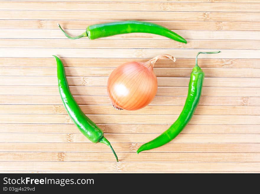 Green chili peppers and onion on a bamboo placemat