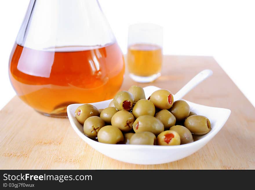 Olives with red peppers and schnapps bottle on wooden bamboo plate. Olives with red peppers and schnapps bottle on wooden bamboo plate