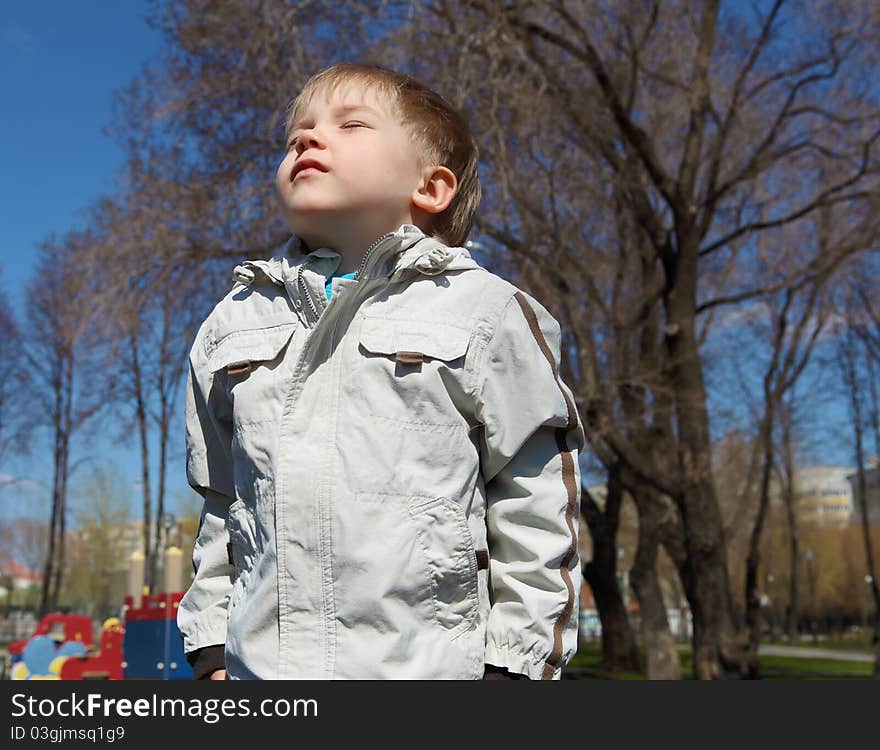 Young boy walks in the park among the trees. Spring mood