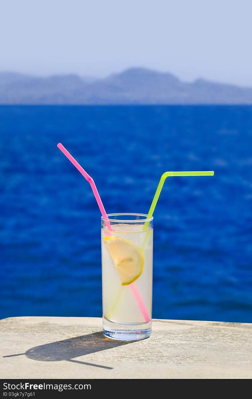 Cocktail on marble table at beach - travel background