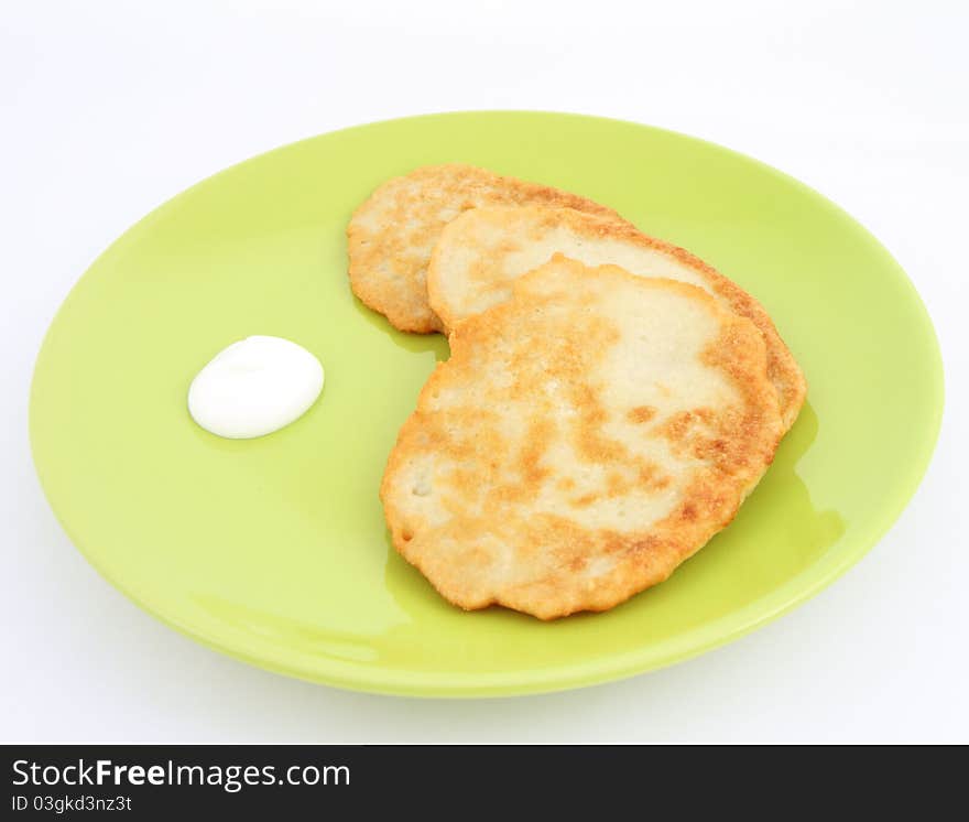 Potato pancakes with cream on white background