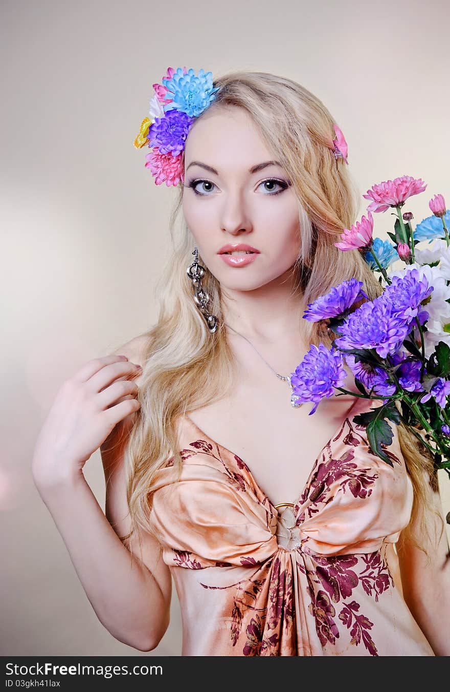 Beautiful young woman with colorful flowers in hair