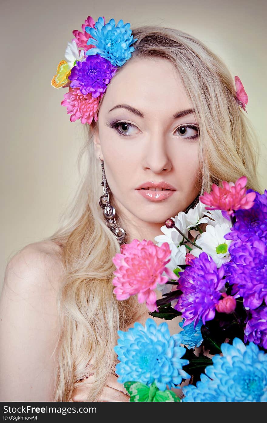 Beautiful young woman with colorful flowers in hair