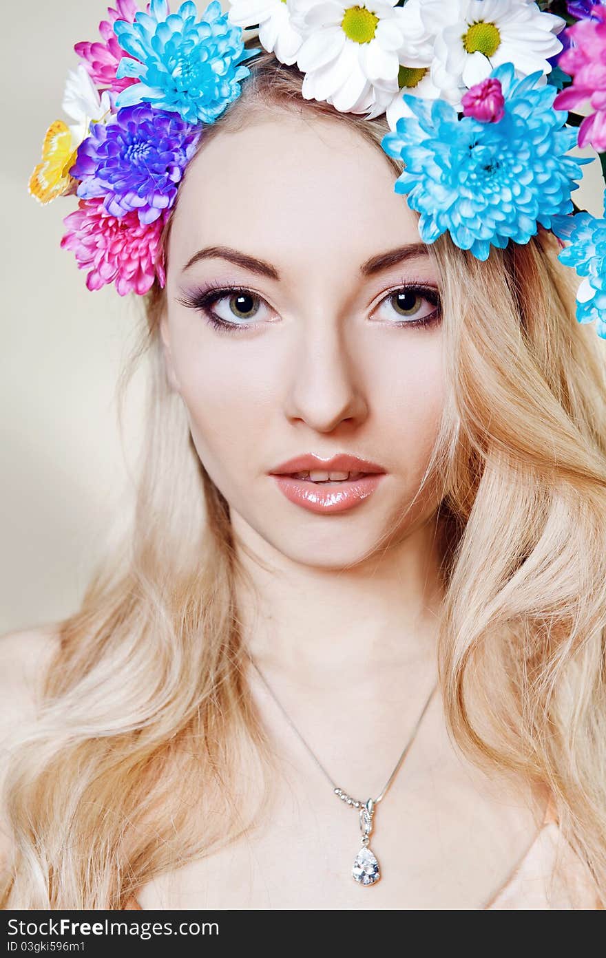 Beautiful young woman with colorful flowers in hair