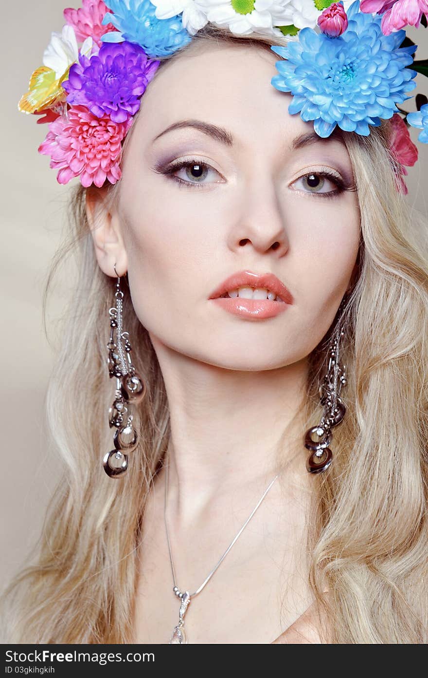 Beautiful young woman with colorful flowers in hair