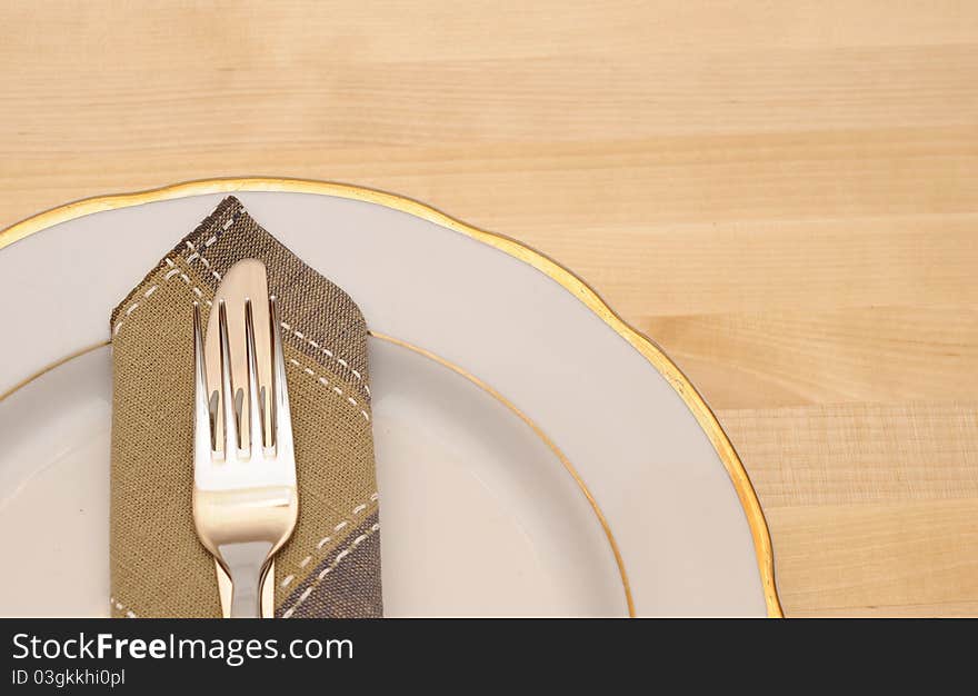 Knife and fork with white plate on wooden table