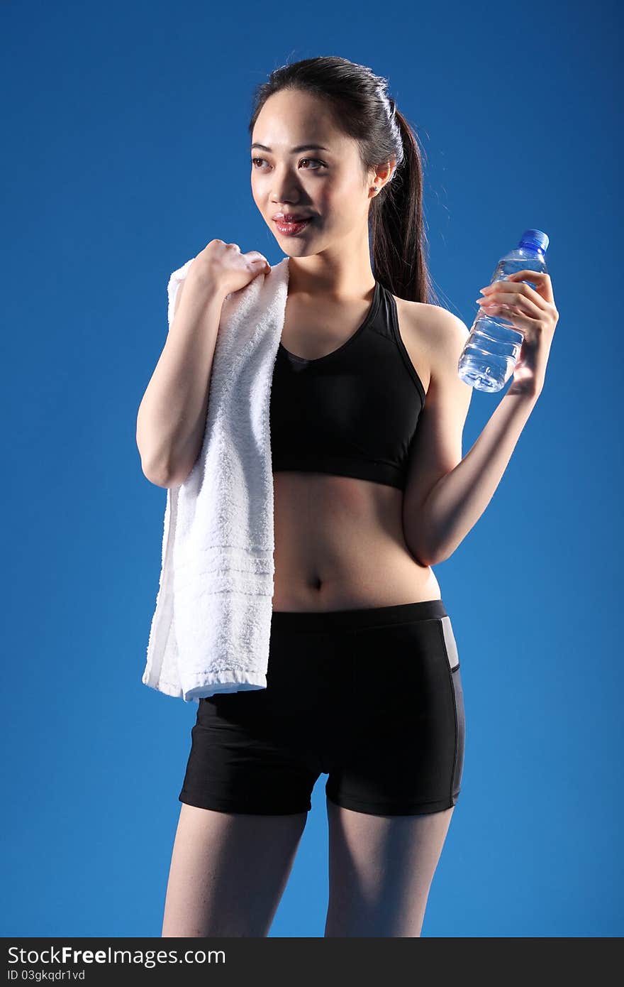 Happy and relaxed after a fitness workout, a beautiful Chinese Asian girl wearing a black sports outfit, standing with bottled water and a towel. Happy and relaxed after a fitness workout, a beautiful Chinese Asian girl wearing a black sports outfit, standing with bottled water and a towel.