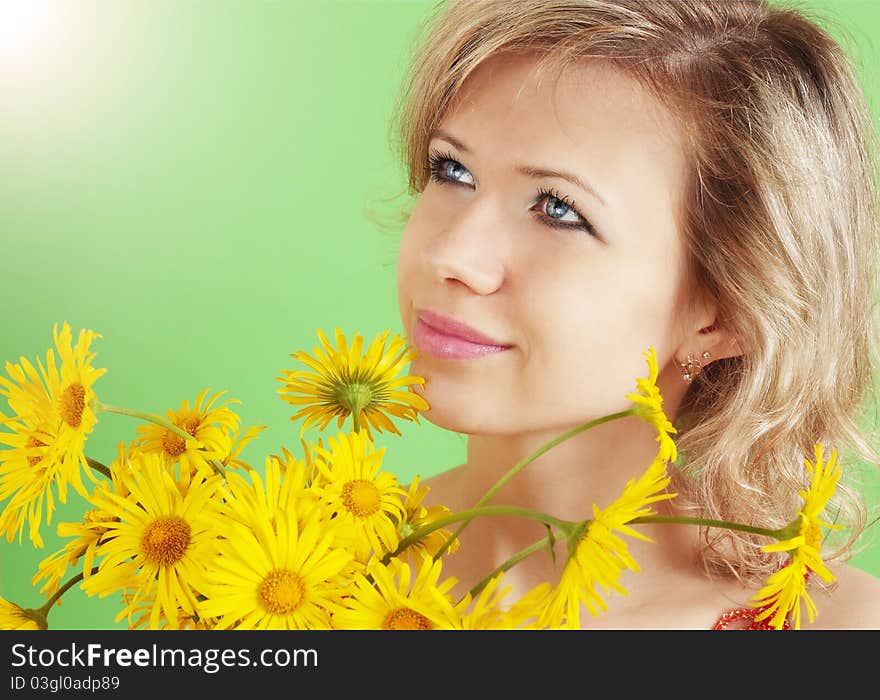 Beautiful blond with the yellow flowers against the green background