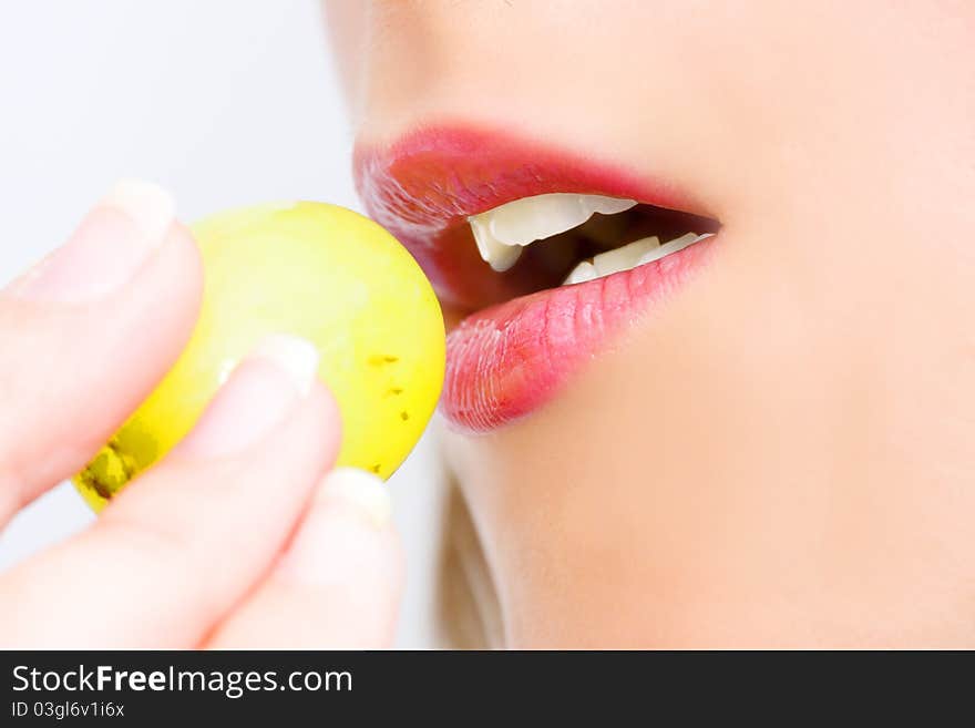 Young woman with grape in her mouth