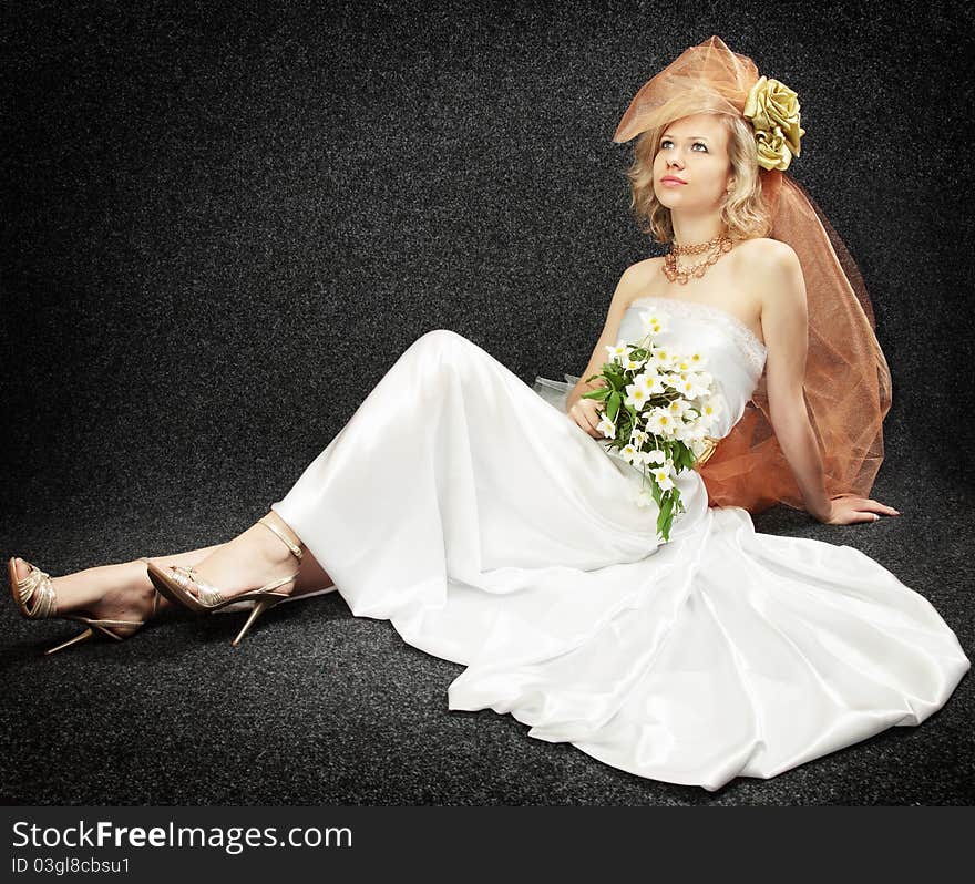 Beautiful bride with the bouquet flowers against the dark background