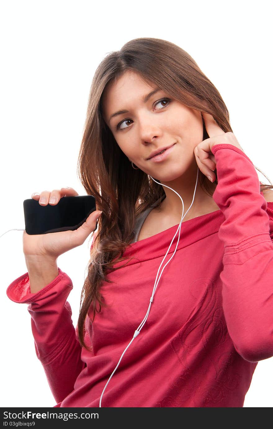 Happy young woman listening, enjoying music and holding cellular mp3 player in earphones on top of her head wearing dance pink top, isolated on white background. Happy young woman listening, enjoying music and holding cellular mp3 player in earphones on top of her head wearing dance pink top, isolated on white background