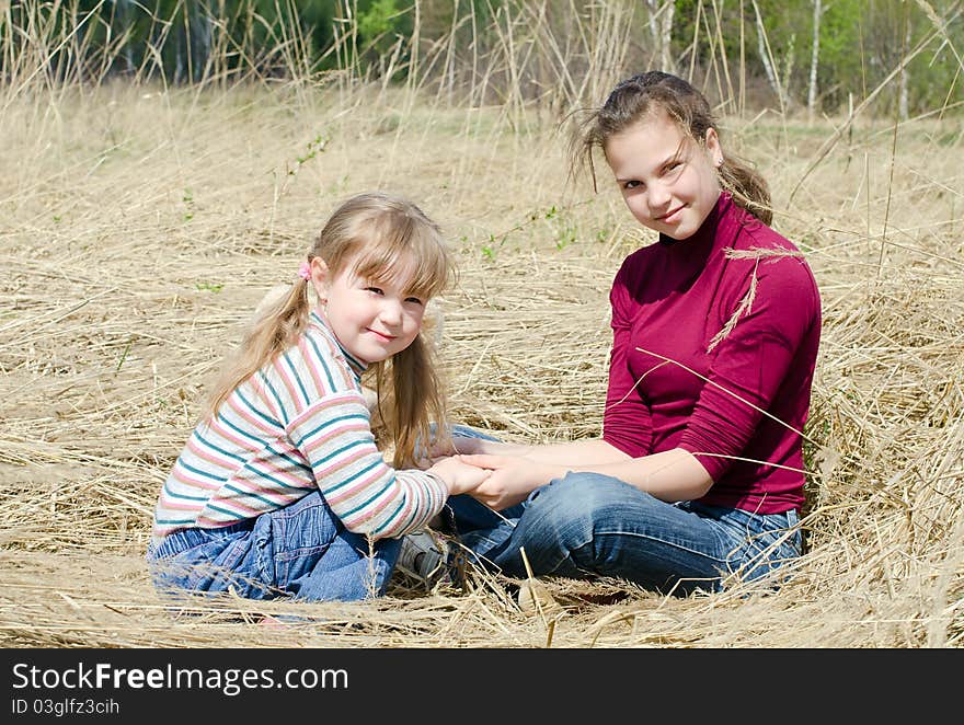 Two beautiful girls on a dry grass