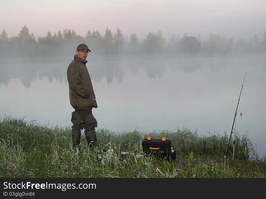 Fisherman on a morning foggy lake