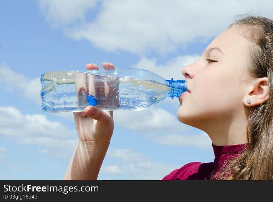 Girl drinks water against the sky