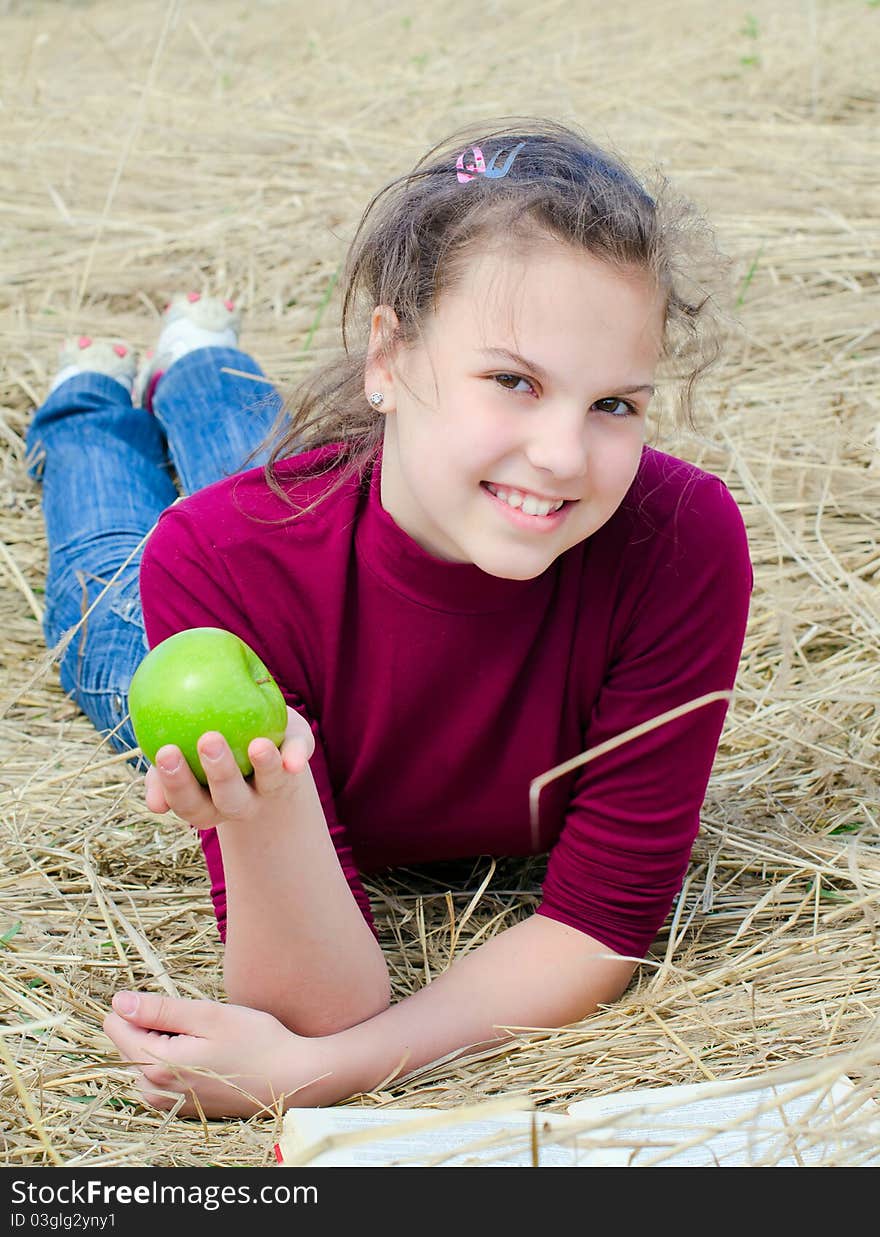 Girl with an apple on dry  grass