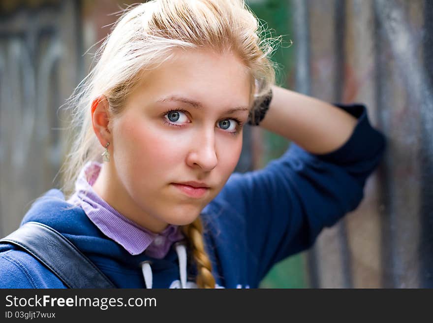 Young teenage girl leaning on a wall and looks at us. Young teenage girl leaning on a wall and looks at us