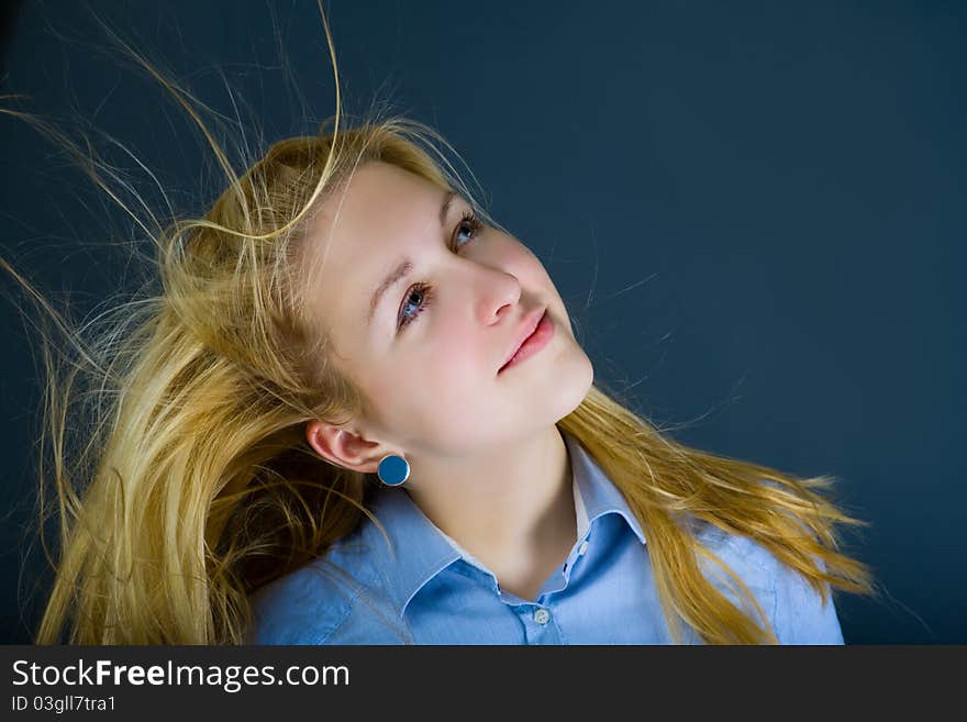 Young teenage girl with flying in the wind blond hair dreamily looking up. Young teenage girl with flying in the wind blond hair dreamily looking up