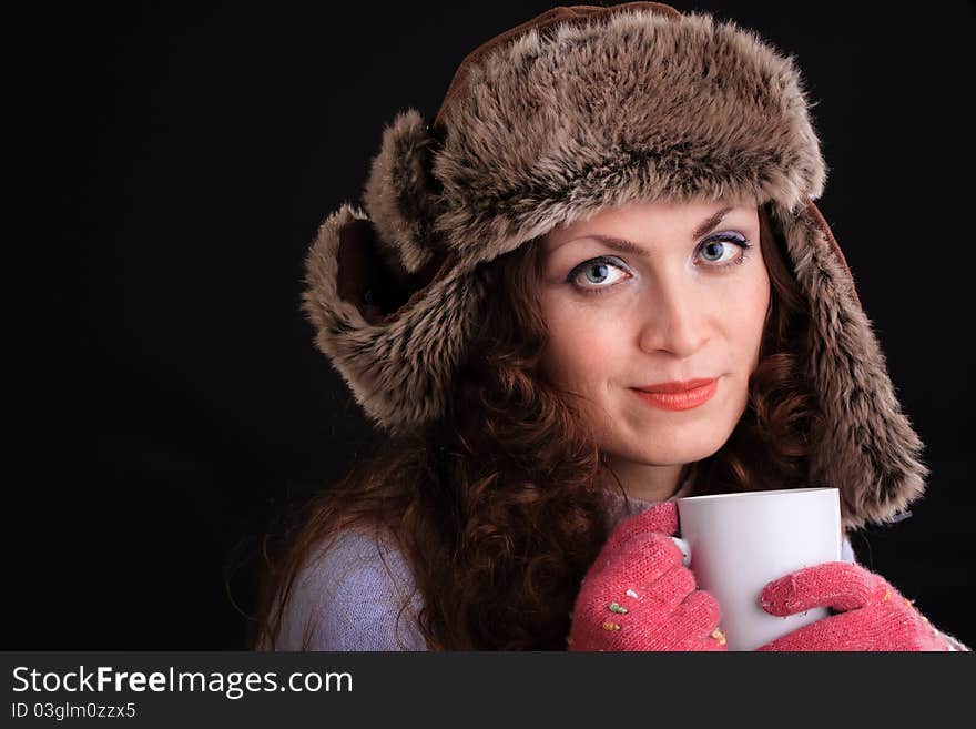 Romantic image of beautiful woman in a fur hat with a cup