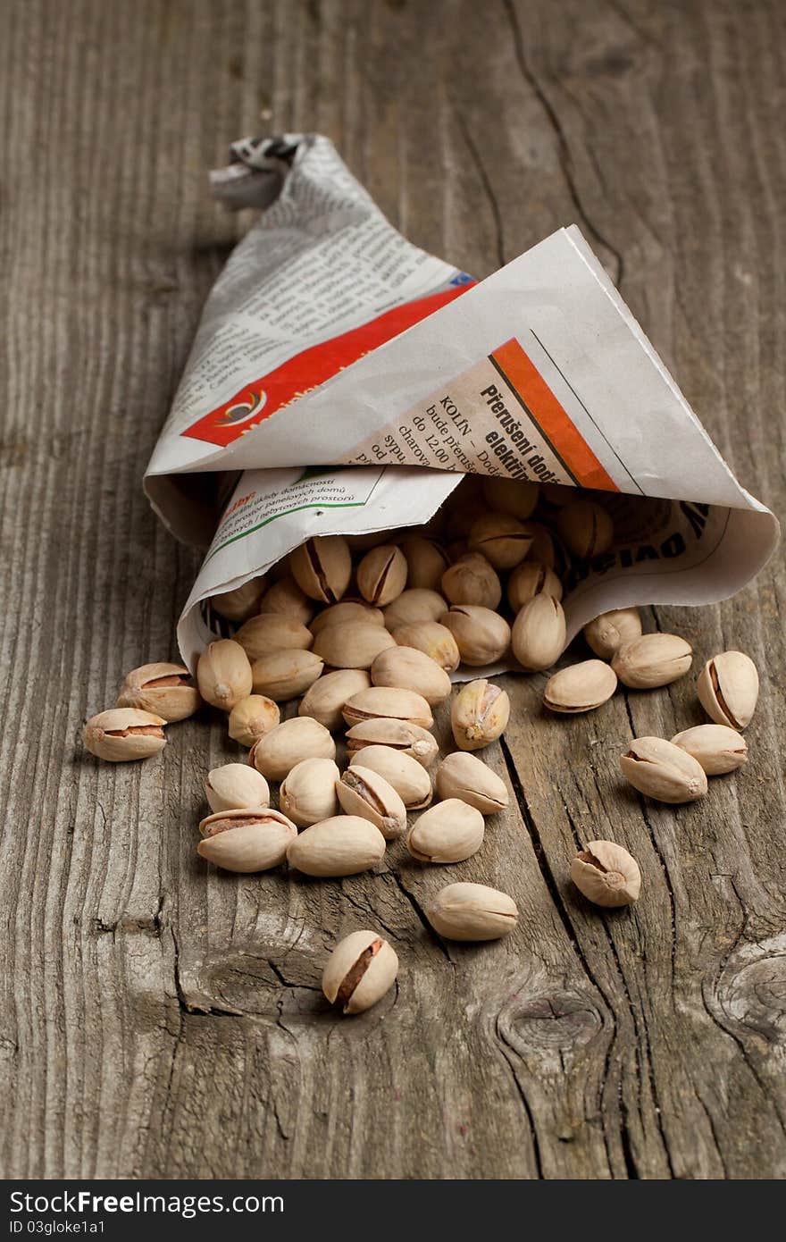 Roasted pistachios from newspaper on old wooden table