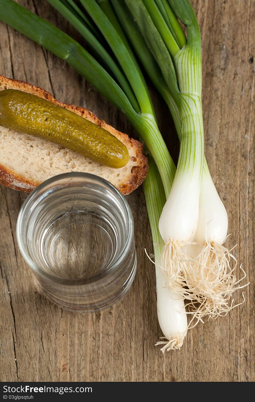 Top view on glass of vodka with cucumber, onion and bread on old wooden table. Top view on glass of vodka with cucumber, onion and bread on old wooden table