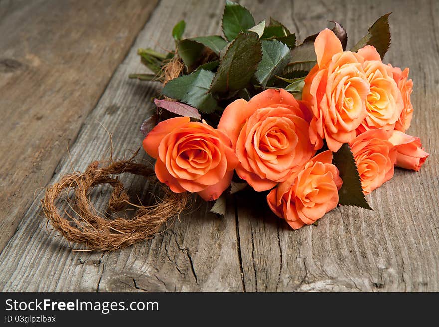 Bunch of orange roses on old wooden table