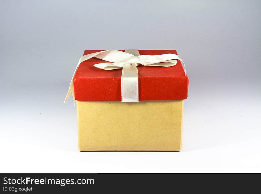 Single red gift box with white ribbon on white background.